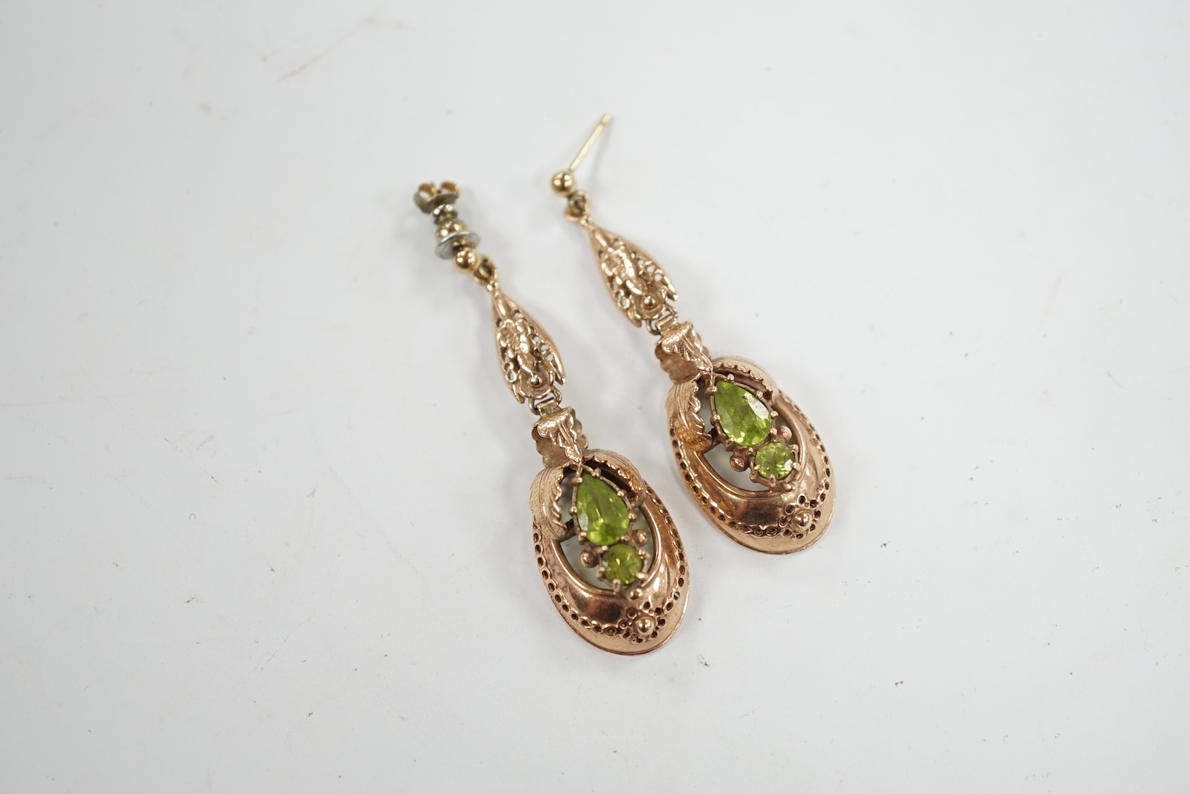 A pair of late 19th/early 20th century style yellow metal and two stone peridot set drop earrings, 48mm. Condition - poor to fair